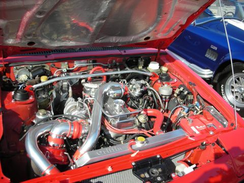 1998 Ford Crown Victoria - detailed engine bay shot of a red car shows twin turbochargers, polished piping, red wiring and a Griffin-branded radiator.