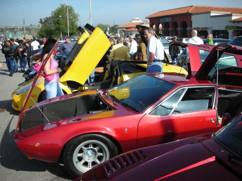 1998 Ford Crown Victoria - maroon wedge-shaped sports car sits in front of a crowd, with a yellow Lamborghini and other cars filling the busy show lot.