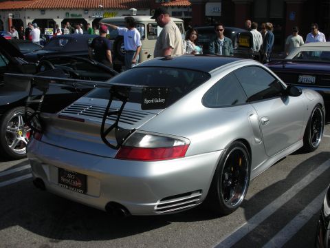 1998 Ford Crown Victoria - silver Porsche 911 with a tall rear wing and Speed Gallery signage is shown from the rear three-quarter at a car meet.