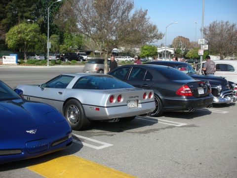 1998 Ford Crown Victoria - silver Chevrolet Corvette C4 with round taillights is parked next to a black Mercedes sedan in a lot.