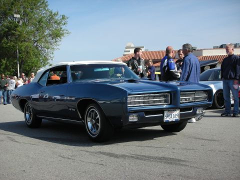 1998 Ford Crown Victoria - dark blue Pontiac GTO with a white roof and GTO badging is parked while people stand nearby at a car show.
