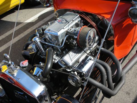 1998 Ford Crown Victoria - Detail of a polished chrome small-block V8 with finned valve covers mounted in an orange Ford hot rod.