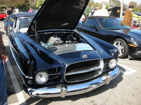 1998 Ford Crown Victoria - dark blue custom coupe with its hood up reveals a chrome carbureted V8 at a sunny car show.