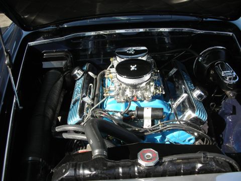 1998 Ford Crown Victoria - Detailed engine bay showing a chrome air cleaner atop a carburetor on a teal-painted V8 with polished accessories.