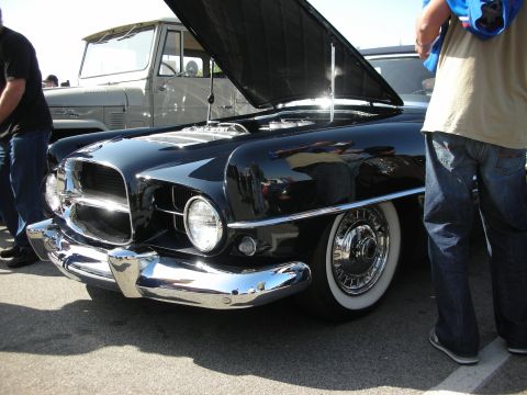 1998 Ford Crown Victoria - Close-up front view of a black classic car with chrome grille, single round headlight and a wide whitewall tire.