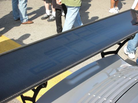 1998 Ford Crown Victoria - large carbon-fiber rear wing mounted on a silver car, with spectators standing behind it on the pavement.