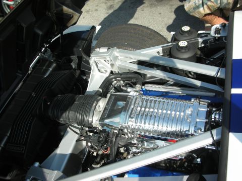 1998 Ford Crown Victoria - polished twin-screw supercharger atop the V8 in the open engine bay of a white-and-blue Ford GT.