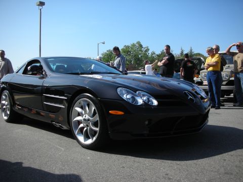 1998 Ford Crown Victoria - black Mercedes-Benz SLR McLaren parked in a lot with spectators and a Jeep in the background.