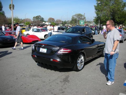 1998 Ford Crown Victoria - Rear three-quarter view of a black Mercedes-Benz SLR McLaren as a man drinks from a bottle beside it.