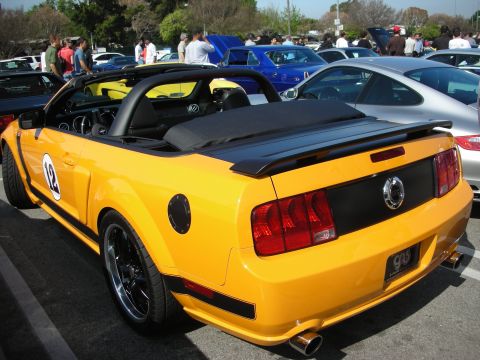 1998 Ford Crown Victoria - Rear three-quarter of an orange-yellow Ford Mustang convertible with a number 12 roundel and black wheels.