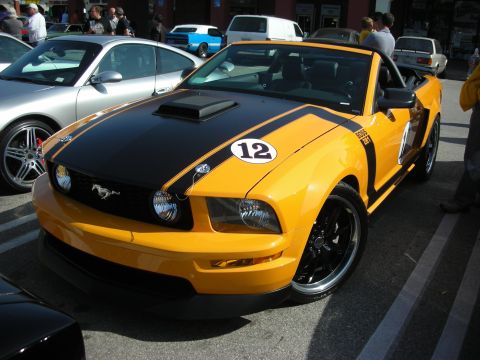 1998 Ford Crown Victoria - orange-yellow Ford Mustang GT convertible with black racing stripes, hood scoop and a number 12 roundel.
