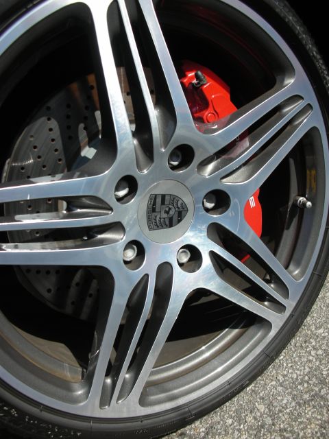 1998 Ford Crown Victoria - Close-up of a Porsche-crested alloy wheel with a red brake caliper and cross-drilled rotor.