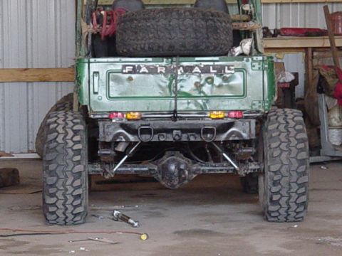 1992 Ford Bronco - Rear view of a green truck with a spare tire mounted and "FARMALL" visible on the tailgate.