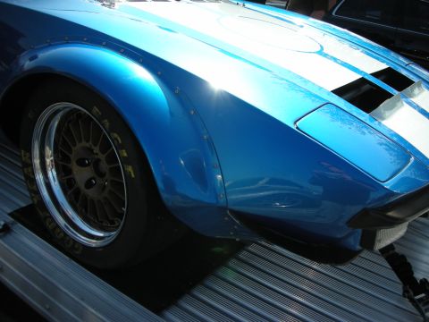 1998 Ford Crown Victoria - blue front fender and wide gold racing wheel of a striped race car sitting on an aluminum trailer.