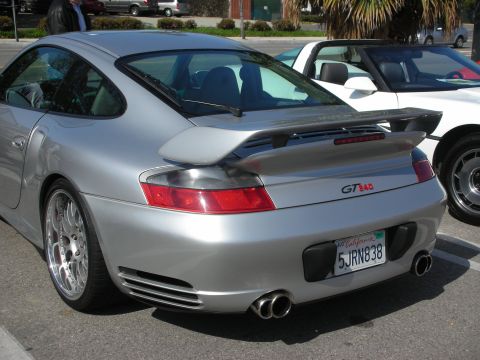 1998 Ford Crown Victoria - silver Porsche 911 coupe with rear wing and GT badge seen from behind in a parking lot.