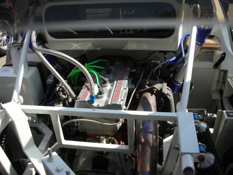 1998 Ford Crown Victoria - Mid-mounted four-cylinder turbo engine sits in the white tube-frame chassis of a race car with blue and braided hoses.