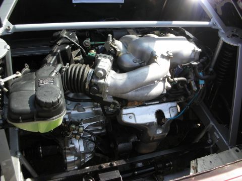 1998 Ford Crown Victoria - mid-mounted engine with cast intake runners and a green-capped reservoir sits in a tube-frame chassis with a green-coral body panel.