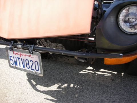 1998 Ford Crown Victoria - Front detail of a coral-bodied car showing its black tube bumper, round headlight, amber turn signal and a California plate reading 5WTV820.