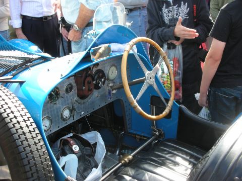 1998 Ford Crown Victoria - spartan open cockpit of a blue vintage Bugatti racer, showing a wood-rimmed steering wheel and a row of round gauges.