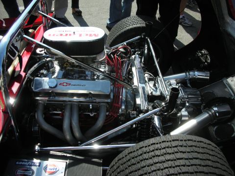 1998 Ford Crown Victoria - Chevrolet V8 topped with a McLaren-branded air cleaner sits mid-mounted in a chrome tube-frame race car beside Goodyear and Gulf decals.