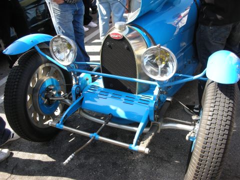 1998 Ford Crown Victoria - Front view of a blue vintage Bugatti grand prix racer showing its horseshoe radiator grille, red Bugatti badge and twin headlights.