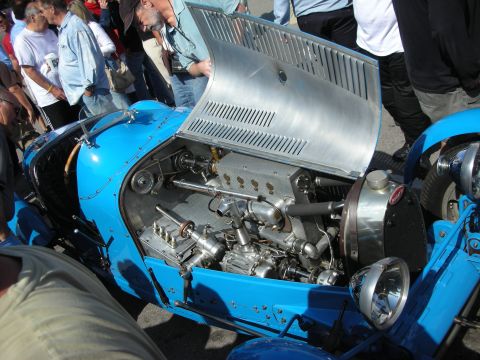 1998 Ford Crown Victoria - light-blue vintage Bugatti racer displays its open engine bay and raised aluminum hood as a crowd looks on.