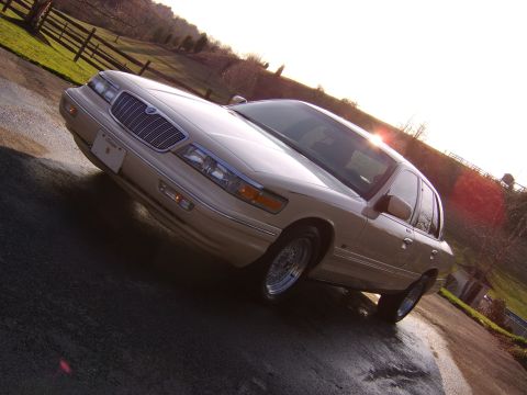 1996 Mercury Grand Marquis - Tan 1996 Mercury Grand Marquis sedan parked on a wet driveway during daytime.