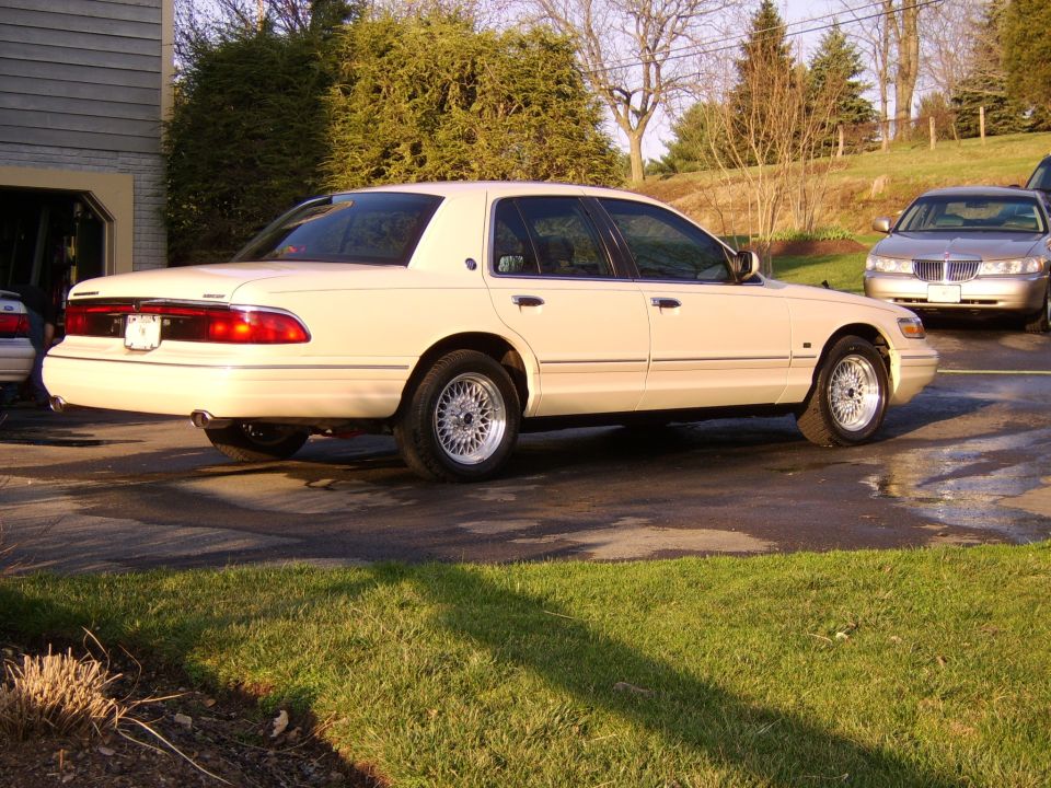 Cream Mercury Grand Marquis sedan rear 3/4 view parked in driveway