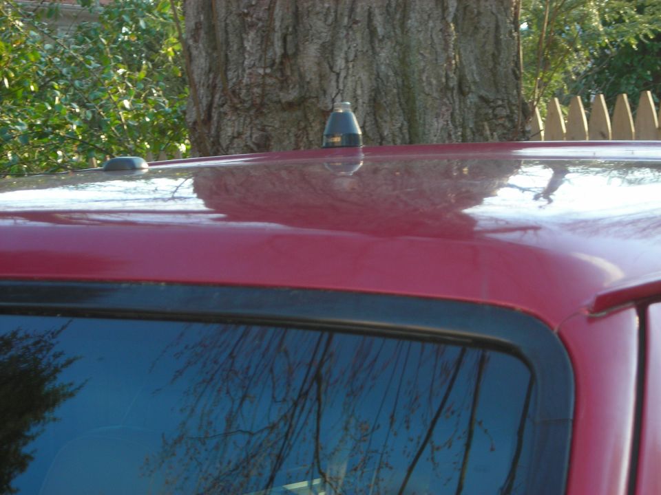 Red SUV roof with a black antenna and a shark fin antenna base
