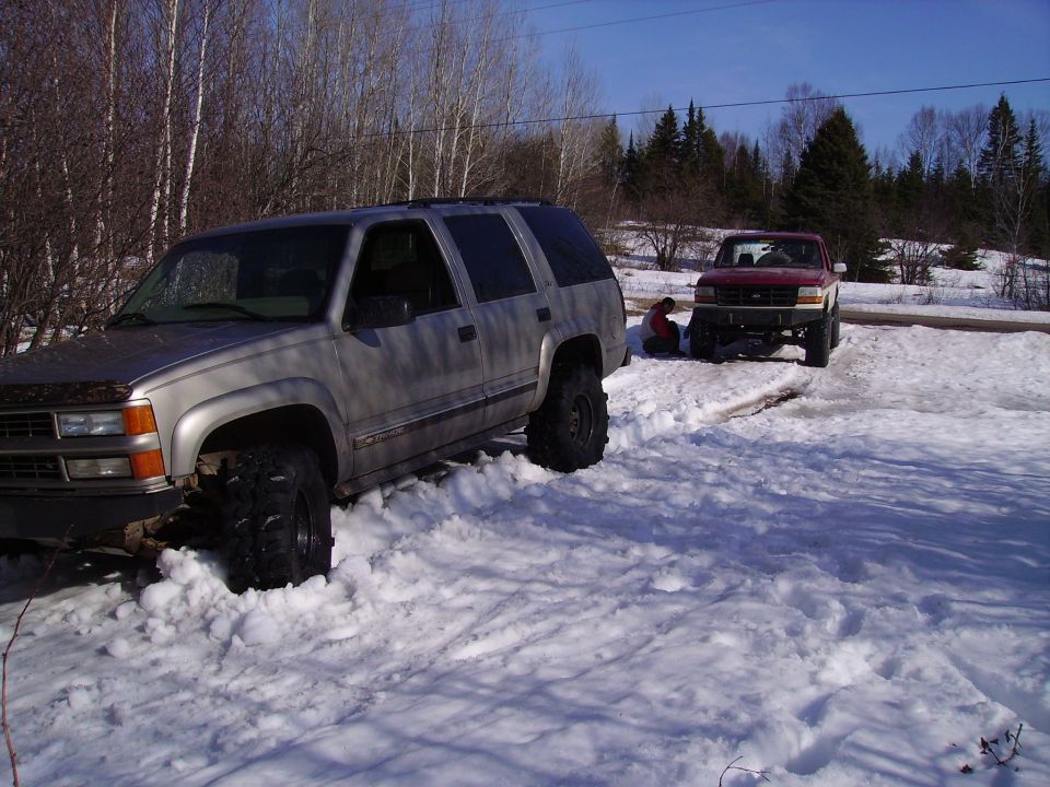 Silver SUV with large tires stuck in deep snow, front end visible