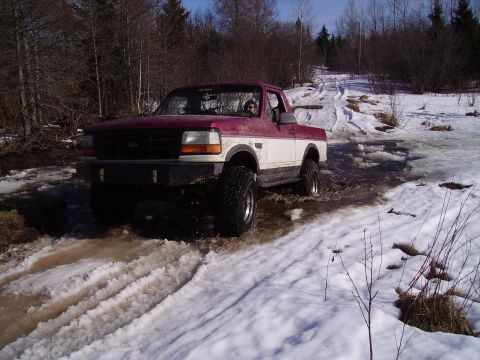 2000 Chevrolet Tahoe - This lifted pickup truck navigates a challenging off-road course with snow and mud.