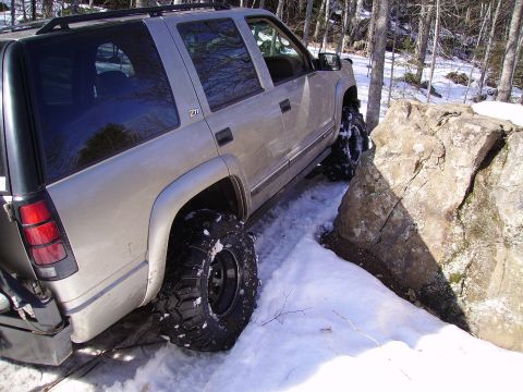 2000 Chevrolet Tahoe - Chevrolet Tahoe with off-road tires maneuvers through snow near a large rock.