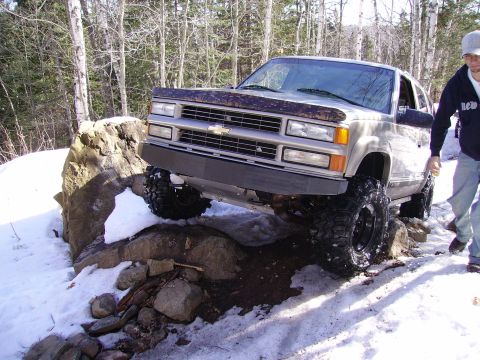 2000 Chevrolet Tahoe - A modified Chevrolet pickup truck is shown off-roading through a snowy, rocky terrain.