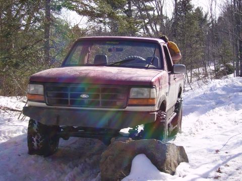 2000 Chevrolet Tahoe - A Ford F-Series truck navigates a snowy path, with a person visible in the passenger seat.
