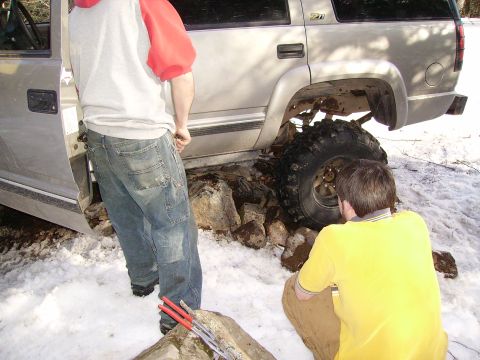 2000 Chevrolet Tahoe - The vehicle appears to be a late 1990s model SUV, possibly a Chevrolet Suburban or Tahoe, stuck on rocks in a snowy environment.