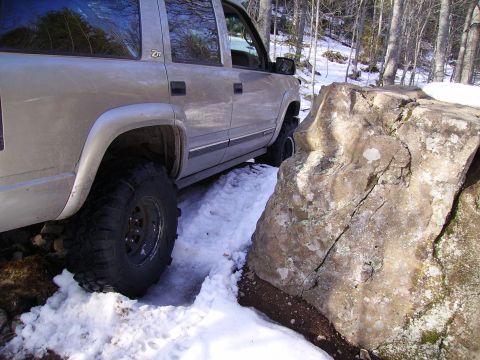 2000 Chevrolet Tahoe - 2000 Chevrolet Tahoe driving through snow and rocks on a wooded trail.