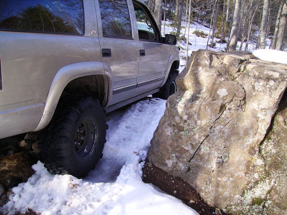 Silver 2000 Chevrolet Tahoe navigating a snowy trail next to a large rock