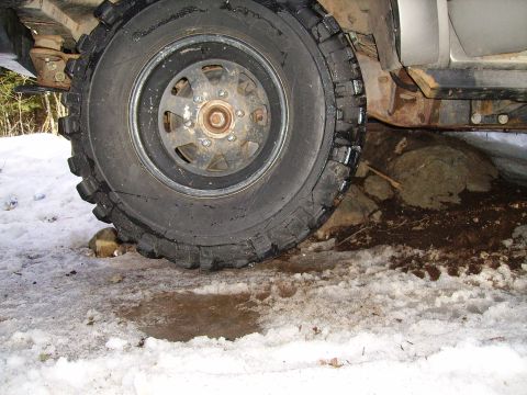 2000 Chevrolet Tahoe - The vehicle's tire is positioned on rocks, with snow and mud visible on the ground, suggesting off-road use.