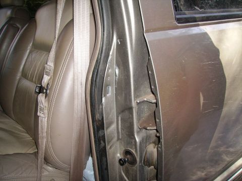 2000 Chevrolet Tahoe - The interior of a 2000 Chevrolet Tahoe shows a beige seatbelt and damage to the driver's side door frame.
