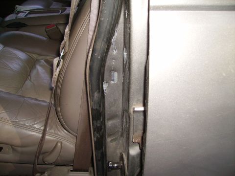 2000 Chevrolet Tahoe - Close-up view of the interior door frame and tan leather seat, showing the seatbelt mechanism.