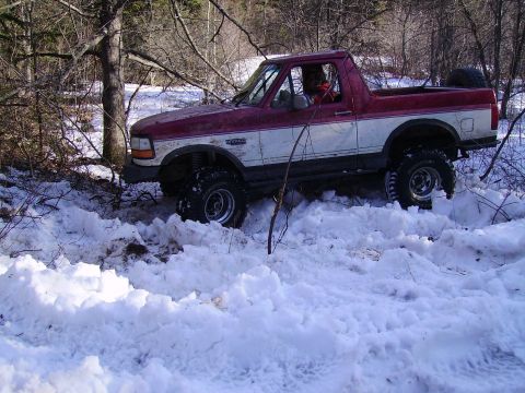 2000 Chevrolet Tahoe - A lifted Ford Bronco navigates through a snowy, wooded area.