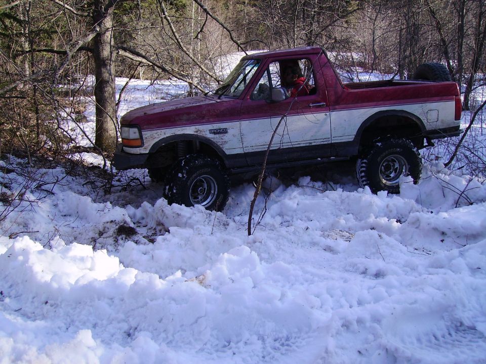 Red and white lifted Ford Bronco in snow