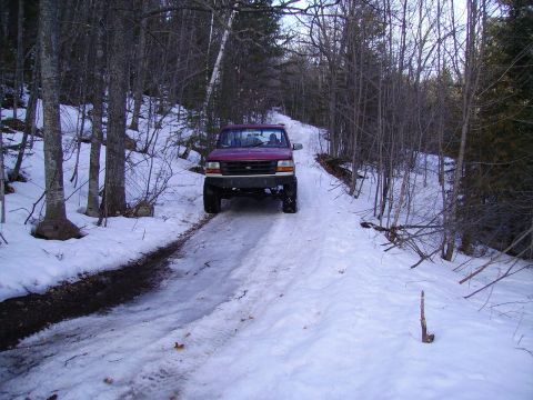 2000 Chevrolet Tahoe - Pickup truck navigates a snowy path in a wooded area during winter.