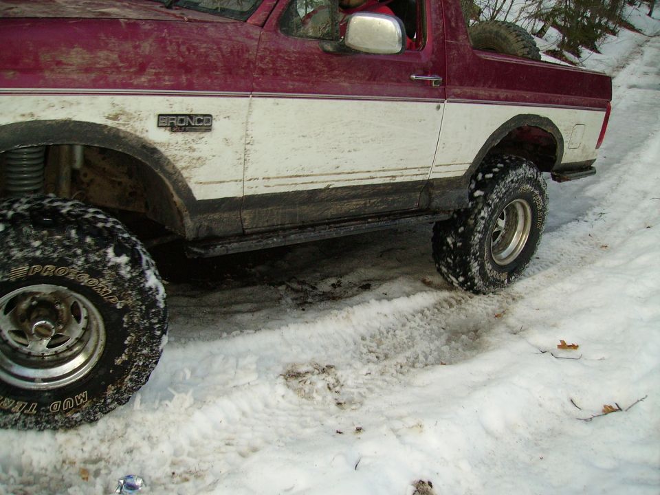 Maroon and white Ford Bronco with off-road tires in the snow