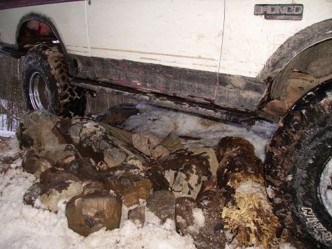 2000 Chevrolet Tahoe - A Ford Bronco is stuck on a pile of rocks and snow, with its tires partially submerged.