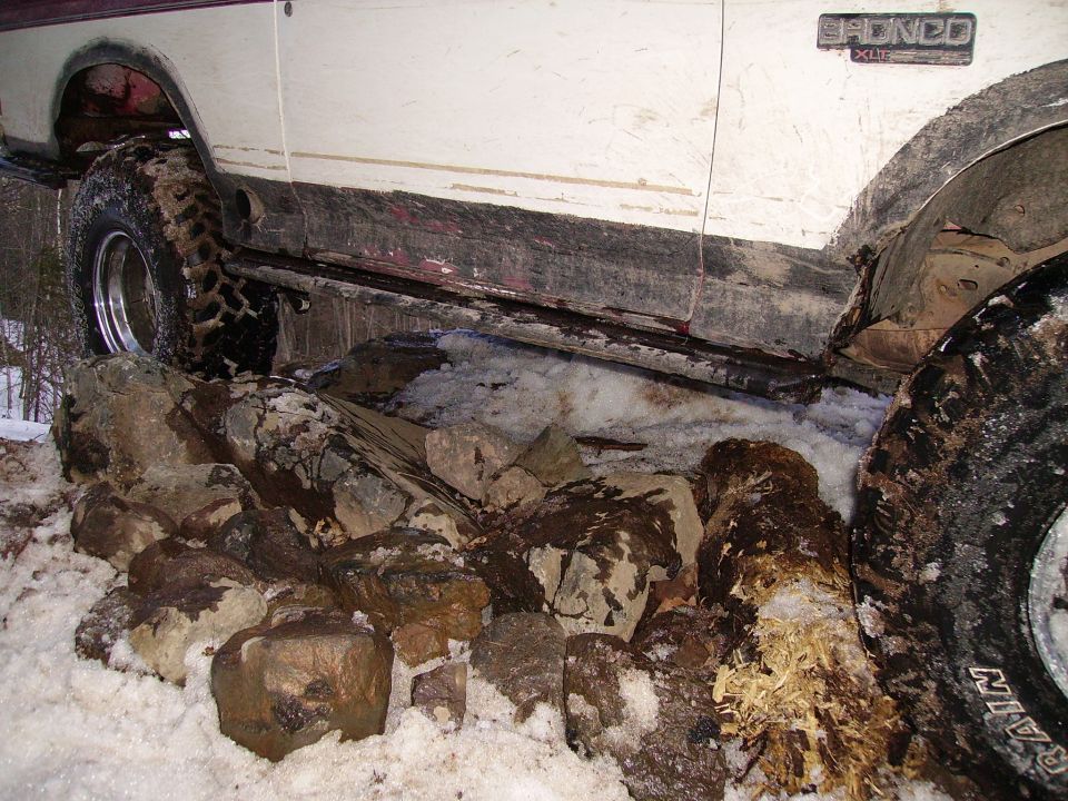 Ford Bronco stuck on rocks and snow. The side of the vehicle shows a "Bronco XLT" badge