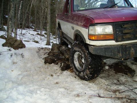 2000 Chevrolet Tahoe - A red and white pickup truck is shown off-road in a snowy, wooded area.