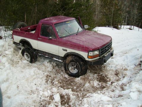 2000 Chevrolet Tahoe - A two-tone Ford Bronco is stuck in a snowy, wooded area.