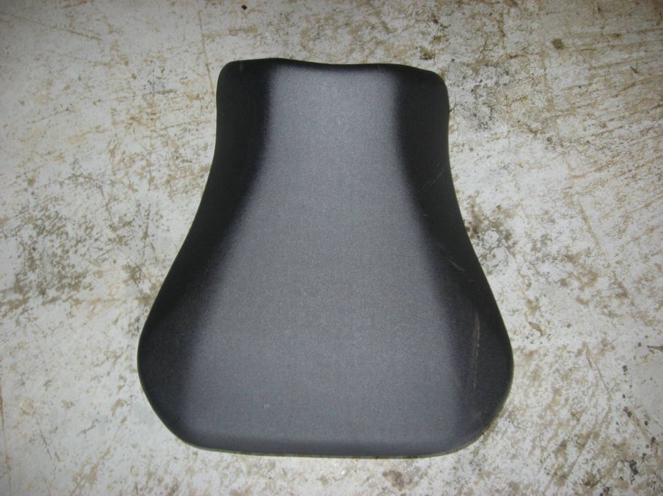 Black motorcycle solo seat resting on a concrete floor