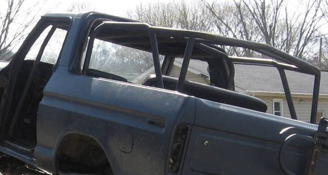 Dark blue 1978 Ford Bronco with a roll cage, viewed from the side